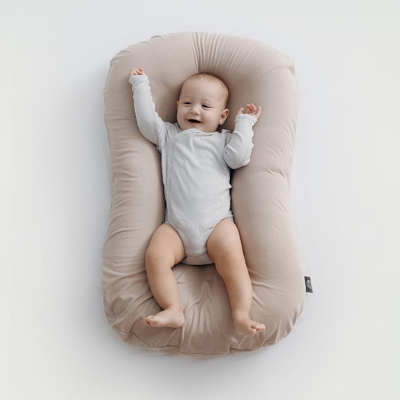 BEBE ALLONGE SUR REDUCTEUR DE LIT BIONICCOCOON™ GRIS BEIGE