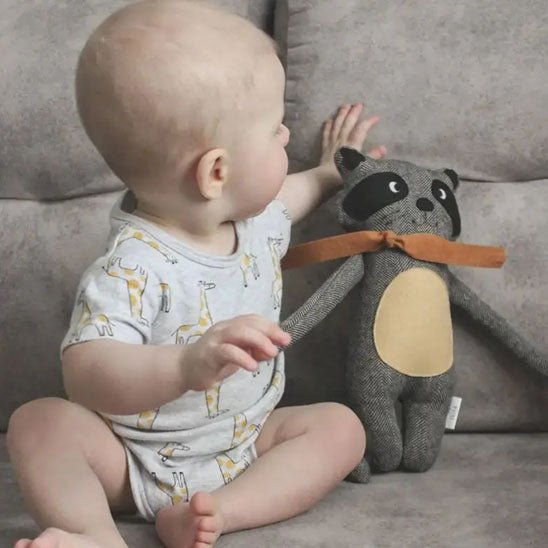 Bébé assis avec notre doudou Raccoon