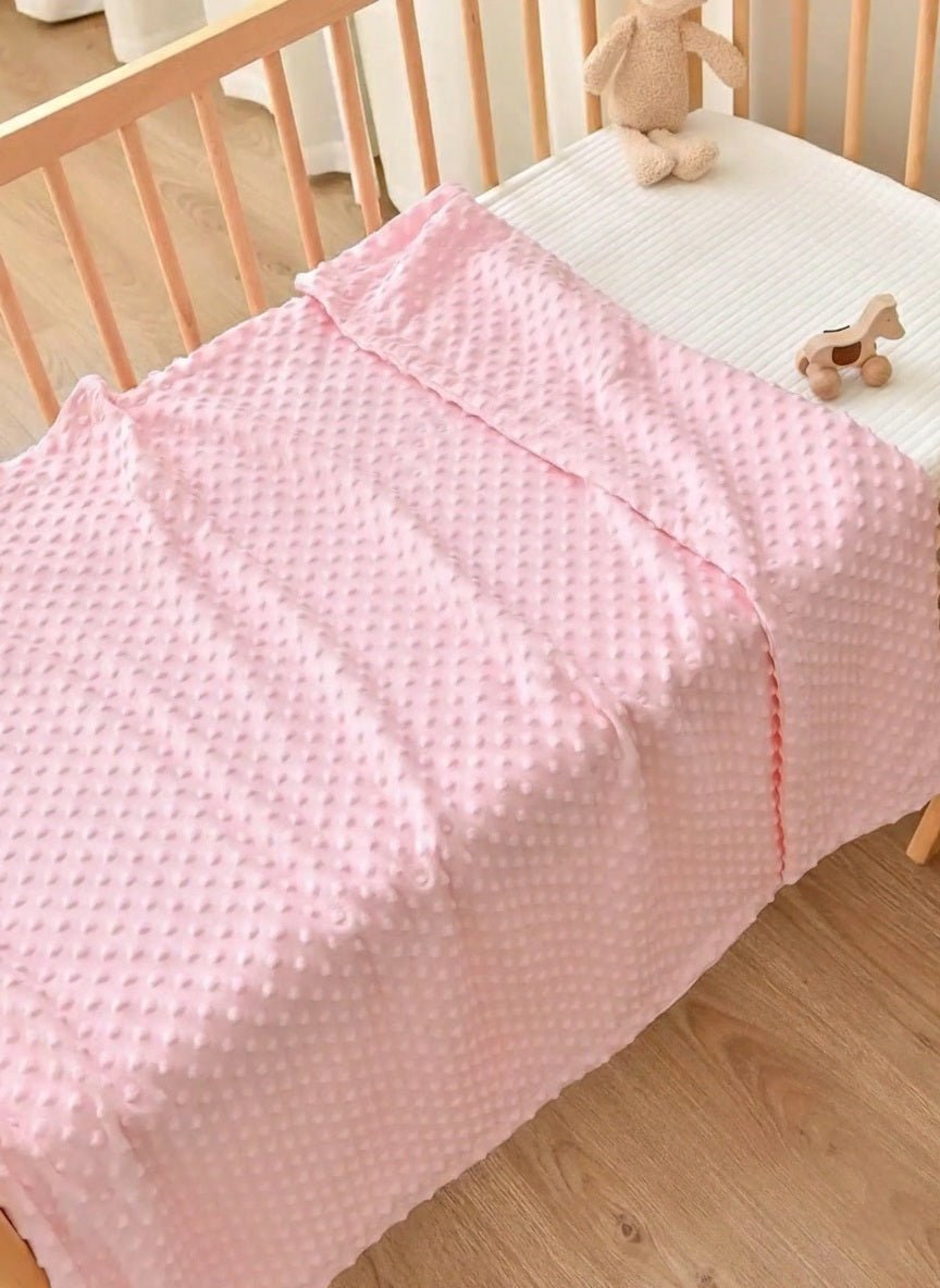 Couverture bébé Bulles douces rose sur un lit