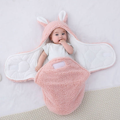 Bébé allongé dans notre couverture d'emmaillotage CuddleBunny™ rose