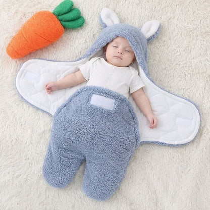 Bébé allongé dans notre emmaillotage couverture CuddleBunny™ bleue