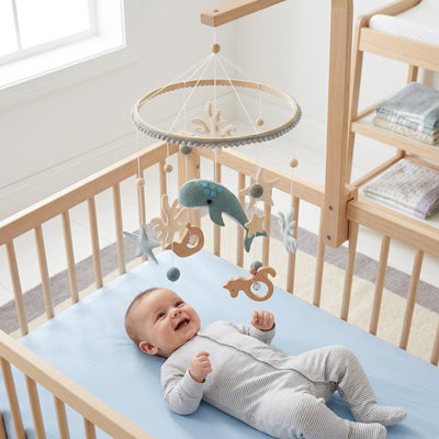 Bébé allongé souriant avec notre mobile bébé DreamyWhale™