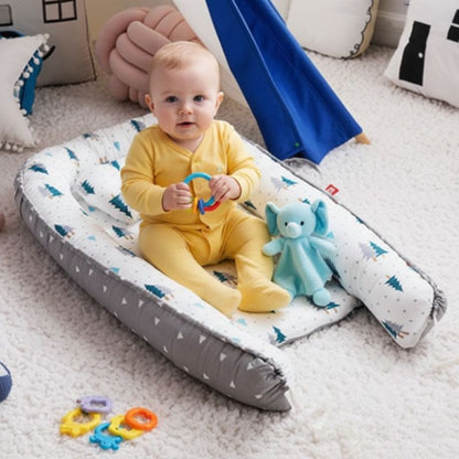 Bébé assis sur notre réducteur de lit bébé Cocon Sapin gris