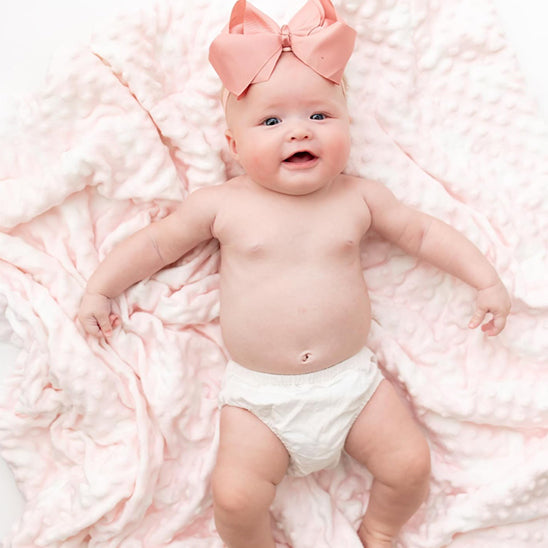 Bébé au sourire et une Couverture bébé RectoBulles rose