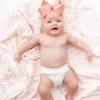 Bébé au sourire et une Couverture bébé RectoBulles rose