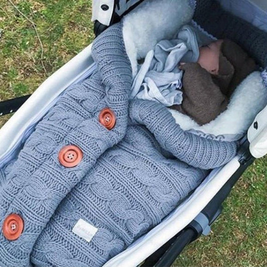 Bébé endormi dans notre couverture emmaillotage CuddleAngel™ bleue dans une poussette