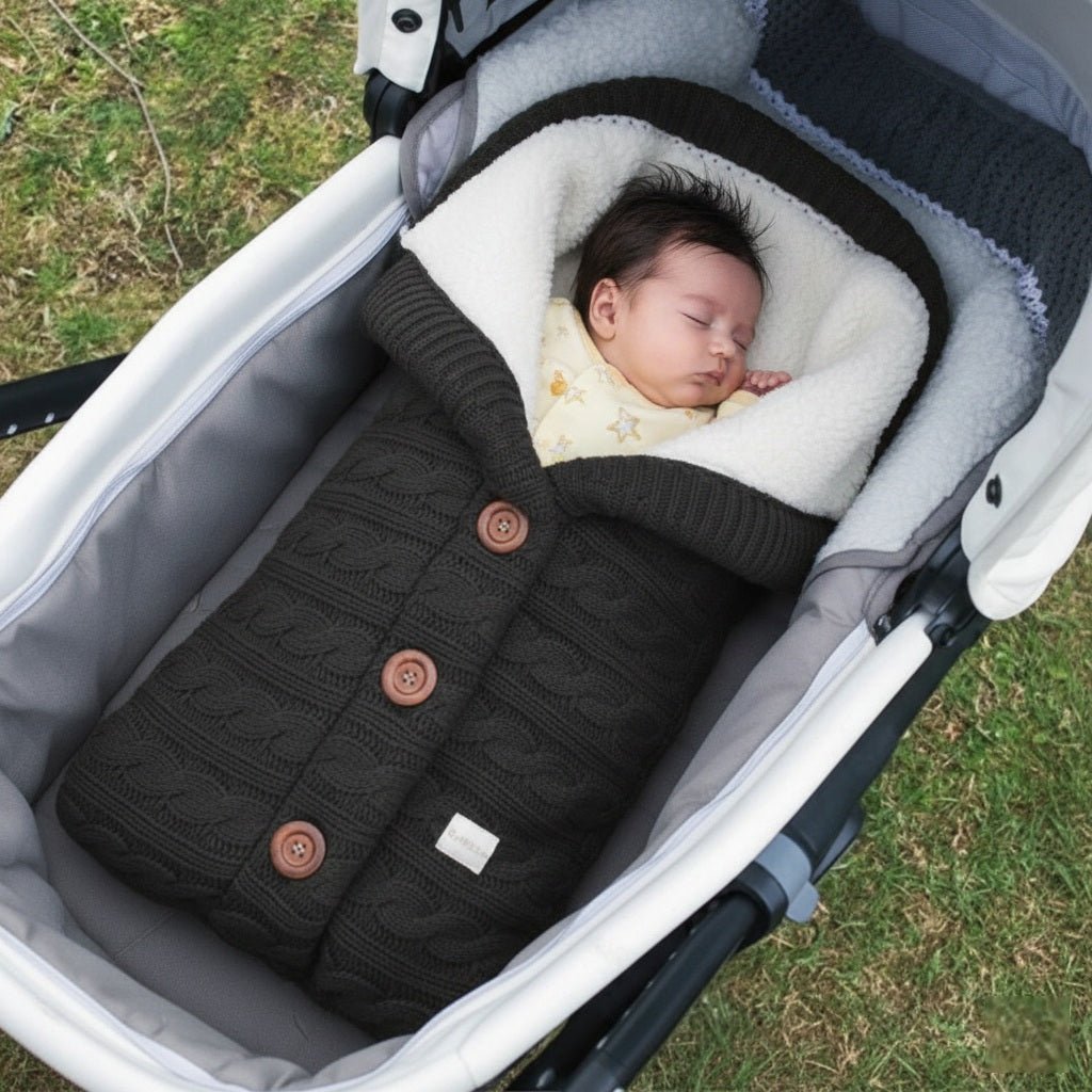 Bébé endormi dans notre couverture emmaillotage CuddleAngel™ noire dans une poussette