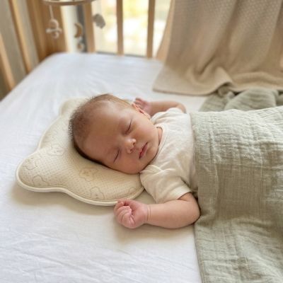 Bébé endormi sur notre coussin bébé anti-tête plate ergonomique et respirant beige ourson