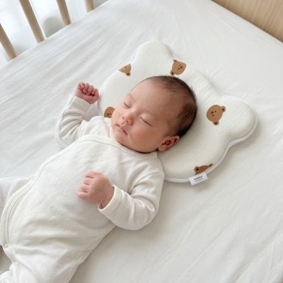 Bébé endormi sur notre coussin bébé anti-tête plate ergonomique et respirant crème