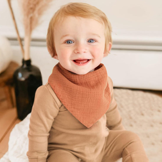 Bébé souriant avec le bavoir bandana orange Cowbaby™
