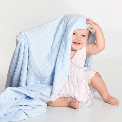 Bébé souriante avec une Couverture bébé RectoBulles bleue